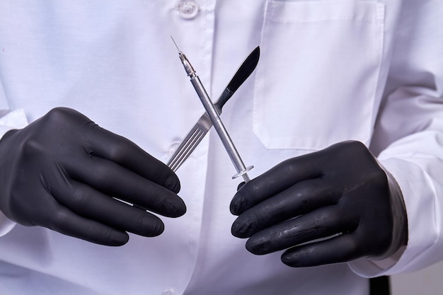 Photo doctor surgeon holds a scalpel with syringe surgical concept instrument