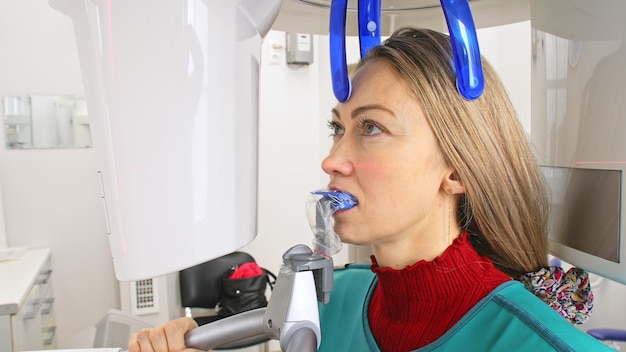現代の実験室歯科医院で歯と顎の3Dスキャナー断層撮影を画像化する医師女性看護師が患者の女性にX線装置3Dデジタルスキャナーコンピューター歯科診断を見せます