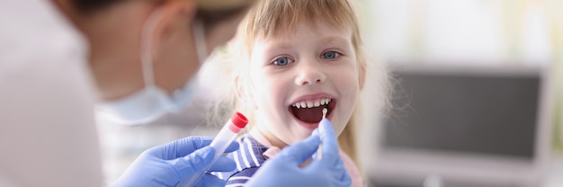 Il dottore prende un'analisi dalla bambina con un batuffolo di cotone