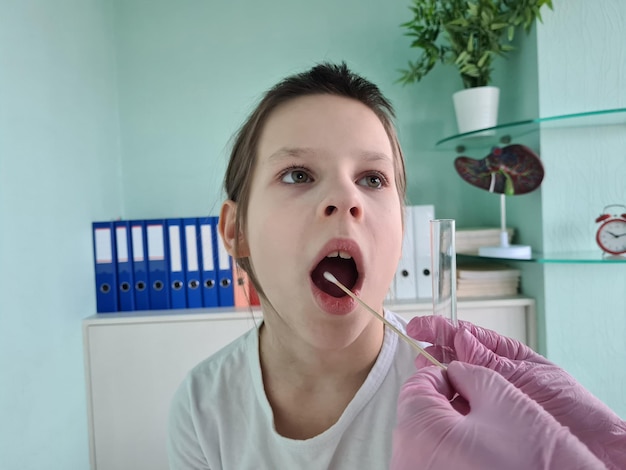 Doctor takes cotton swab from child mouth and analyzes saliva