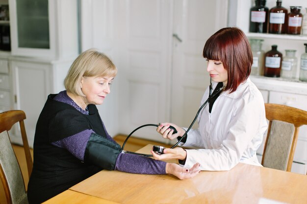 Doctor taking blood pressure of female patient at office