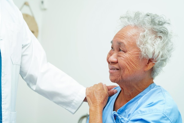 Doctor taking care help and encourage Asian elder senior woman patient in clinic hospital