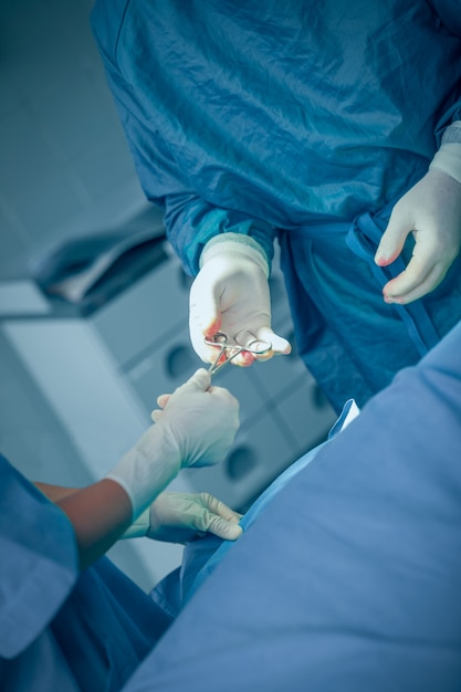 Doctor taking a scissors from the hand of a nurse