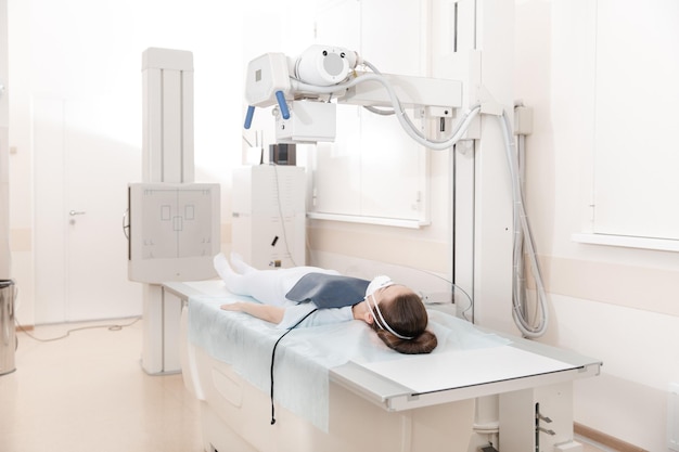 Photo doctor taking x-ray of patient lying on gurney hospital radiology room x-ray machine