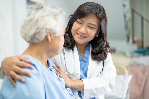 Doctor talking about diagnosis and note on clipboard with Asian senior or elderly old lady woman while lying on bed in nursing hospital ward healthy strong medical concept