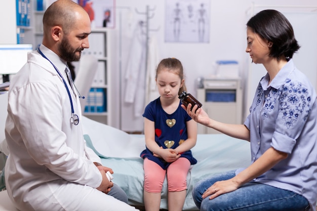 Doctor talking about diagnostic and treatment with mother of child in medical office. Practitioner pediatrician specialist in medicine providing professional healtcare services