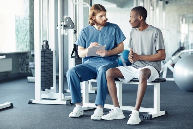 Doctor talking to patient in gym