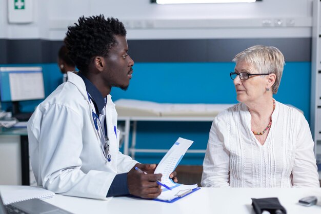 Photo doctor talking with patient in clinic