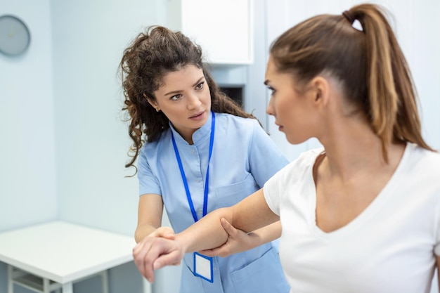 Doctor teaching young woman to do osteoporosis treatment exercise in modern clinic Physiotherapist helping female patient during muscle rehabilitation physiotherapy