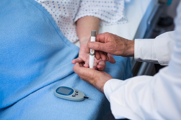 Doctor testing diabetes of senior patient with insulin pen