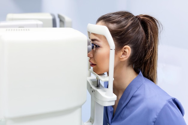 Foto test medico per gli occhi con un apparato ottico speciale nella clinica moderna oftalmologo che esamina gli occhi di un paziente utilizzando il microscopio digitale durante una visita medica nell'ufficio oftalmologico