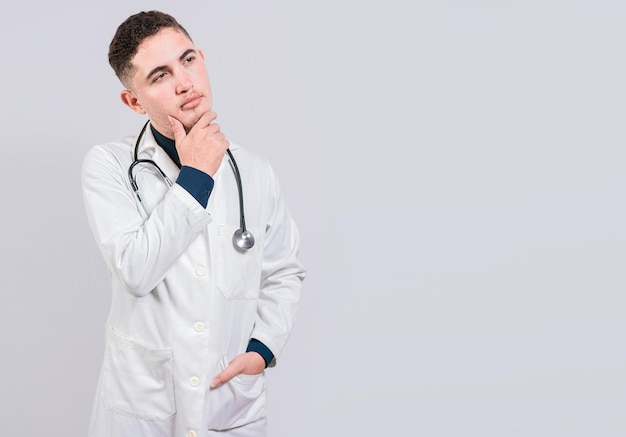 Doctor thinking with hand on chin Pensive doctor man looking up Young doctor thinking and looking up isolated