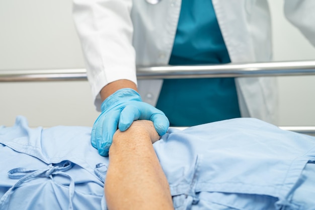 Doctor touching hands Asian senior or elderly old lady woman patient with love care encourage and empathy at hospital