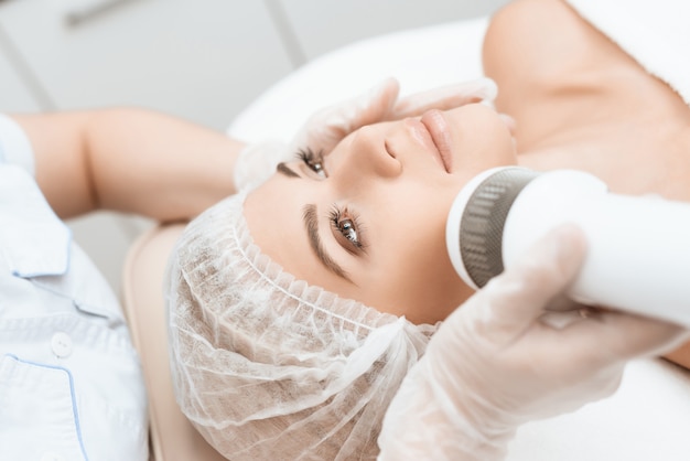 Foto il medico tratta il viso della donna in salone.