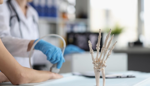 Foto il medico esegue l'ecografia del modello della mano scheletrica sulla scienza dell'anatomia medica della scrivania