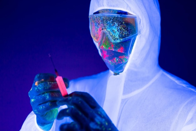 Doctor in ultraviolet neon light is holding COVID19 soronavirus vaccine and syringe using