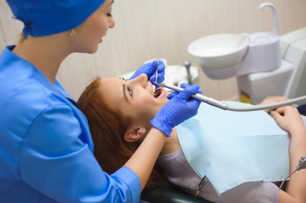 Doctor in uniform checking up female patient's teeth in dental clinic