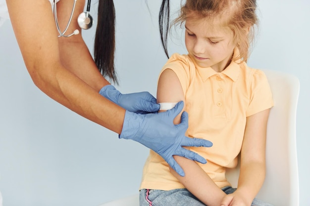 Photo doctor in uniform making vaccination to the little girl