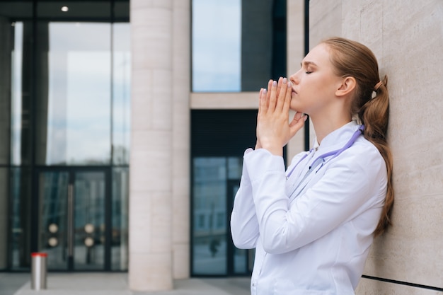 Doctor in uniform praying during an outbreak