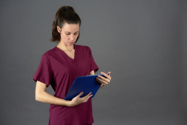 Medico in uniforme viola guardando referto medico su appunti blu con spazio copia lato donna