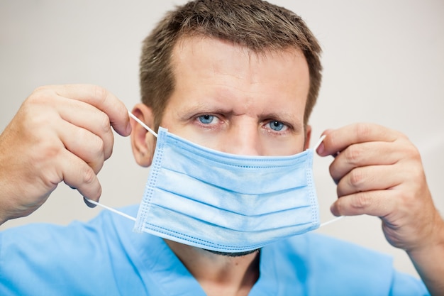 Doctor in uniform putting on a medical mask