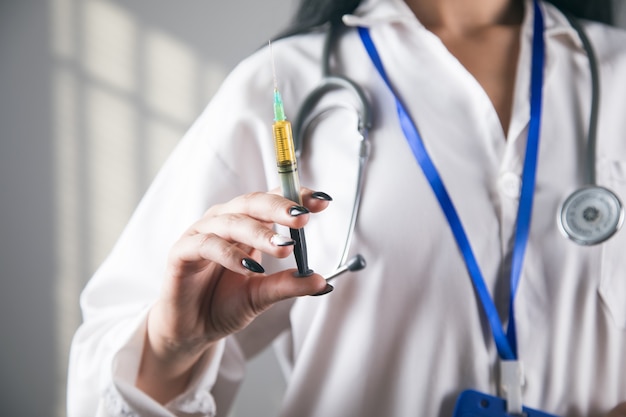 A doctor in uniform stands with a syringe