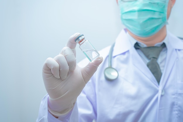 Il medico in uniforme con stetoscopio tiene la vaccinazione coronavirus