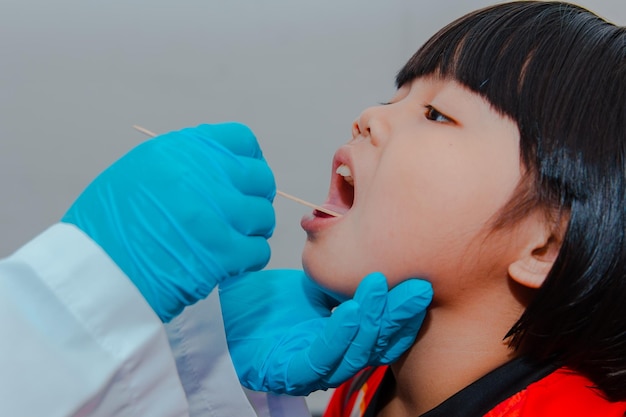 The doctor uses a tongue depressor to examine the child's tongue