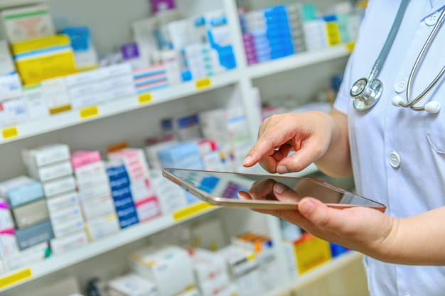 Doctor using computer tablet for search bar on display in pharmacy drugstore shelves.Online medical concept.