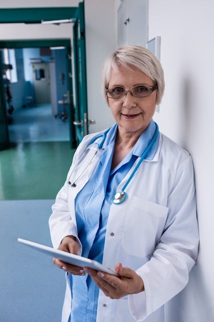 Doctor using digital tablet in corridor