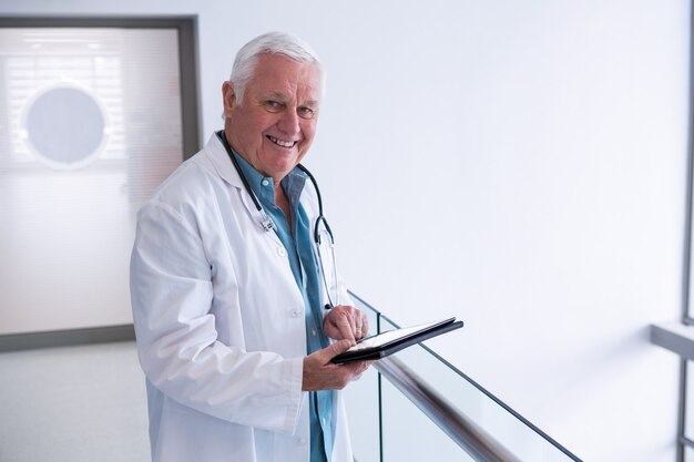 의사가 병원에서 통로에 디지털 태블릿을 사용