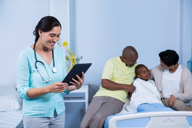 Doctor using digital tablet while parents interacting with patient