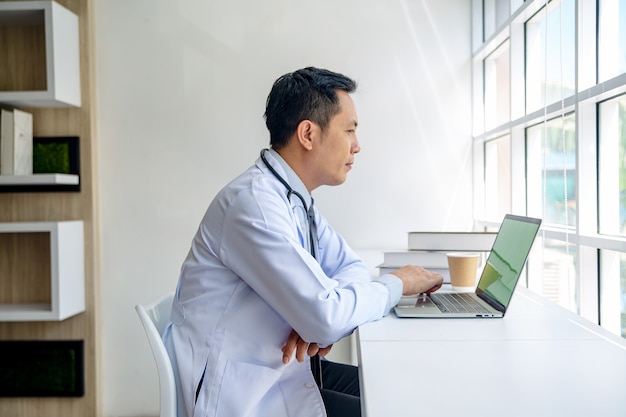 Medico che utilizza laptop in ufficio.