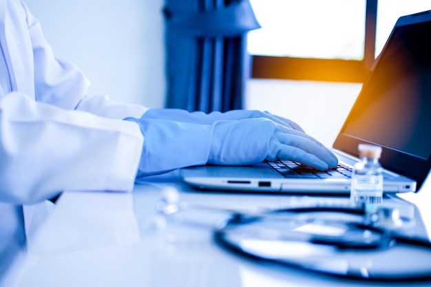 Doctor using a laptop for typing data description into a server computer in hospital Concept invented a cure vaccine for coronavirus disease COVID19 Closeup Selective focus Blurred background