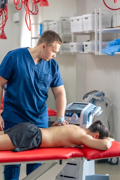 Doctor using machine to treat the back of a patient