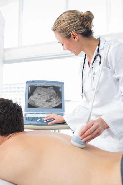 Photo doctor using sonogram on back of male patient