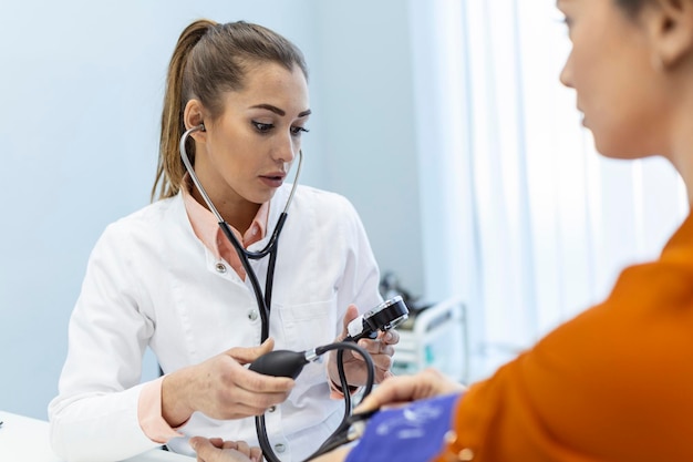 Doctor using sphygmomanometer with stethoscope checking blood pressure to a patient in the hospital