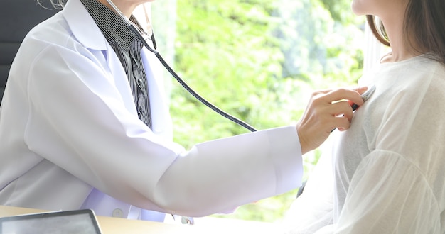 Doctor using stethoscope for examining patient  in his office at Hospitals