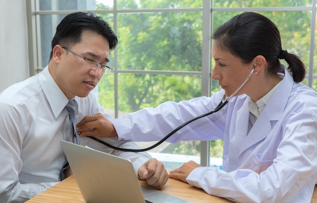 Doctor using the stethoscope listen to heartbeat of man patient with heart disease 