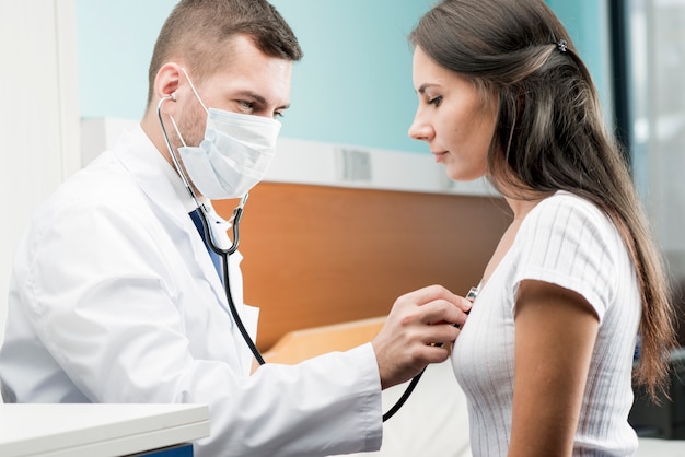 Doctor using stethoscope on patient