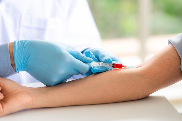 Photo doctor using syringe takes blood from patient arm