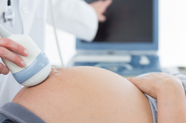 Doctor using ultrasound scanner on pregnant woman 