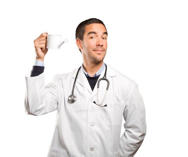 Doctor using a watering can against white background