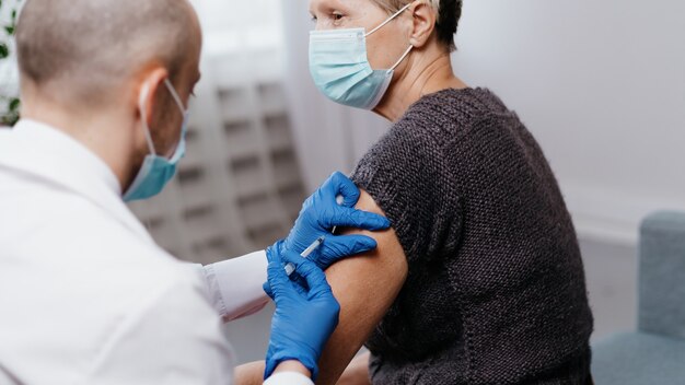 Doctor vaccinating a mature woman against the coronavirus