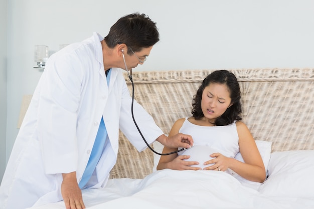 Doctor visiting pregnant woman in bedroom