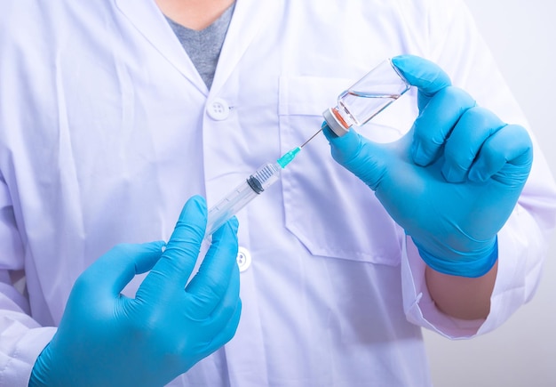 Doctor wearing blue gloves is holding virus vaccine Corona and syringes