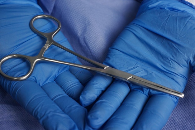 Photo doctor wearing blue medical gloves holding allis intestinal and tissue grasping forceps