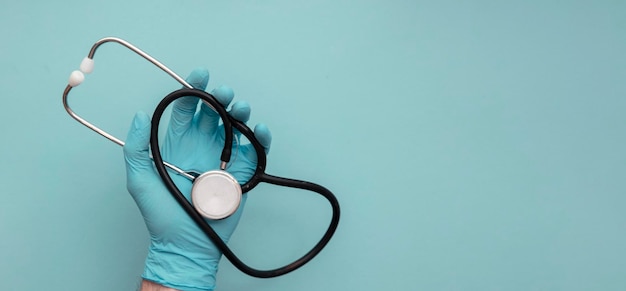 A doctor wearing blue surgical gloves holding a medical stethoscope