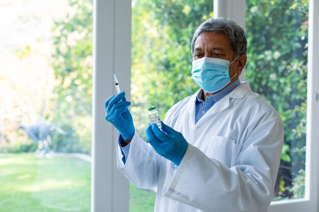 Photo doctor wearing face mask, preparing coronavirus vaccination on his own