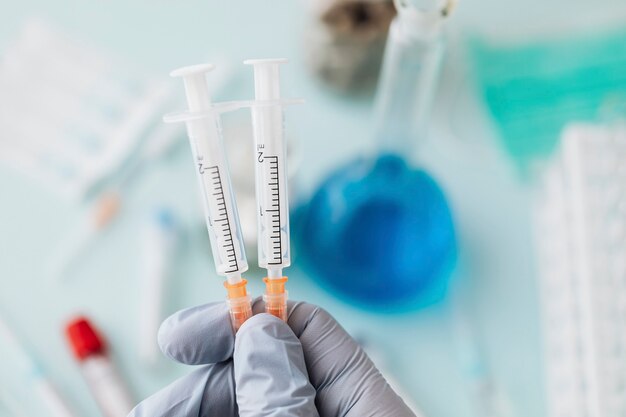 Doctor wearing latex gloves holding syringes